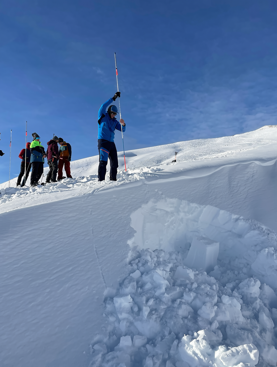Bergkompass: Lawinen- bzw. LVS‑Kurs, bei dem Teilnehmende das Sondieren und die Verschüttetensuche üben – durchgeführt auf einem winterlichen Grat bei bestem Wetter