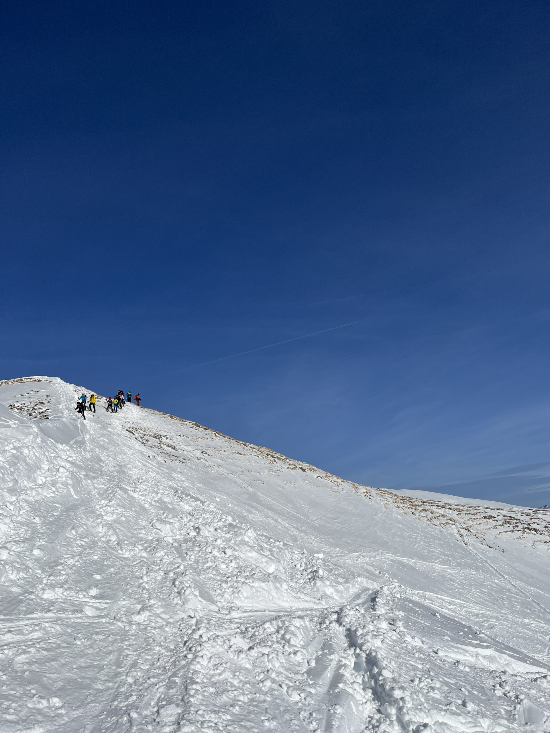 Wandernde Gruppe beim sicheren Abstieg mit Schneeschuhen vom Hählekopf ins Kleinwalsertal, Abendlicht und weite Bergkulisse – fotografiert von Bergkompass Bergwanderführer Pascal Schirmer